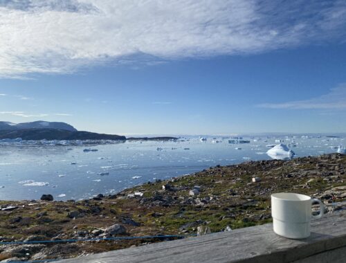 en kop kaffe på rækværket med udsigt over havet